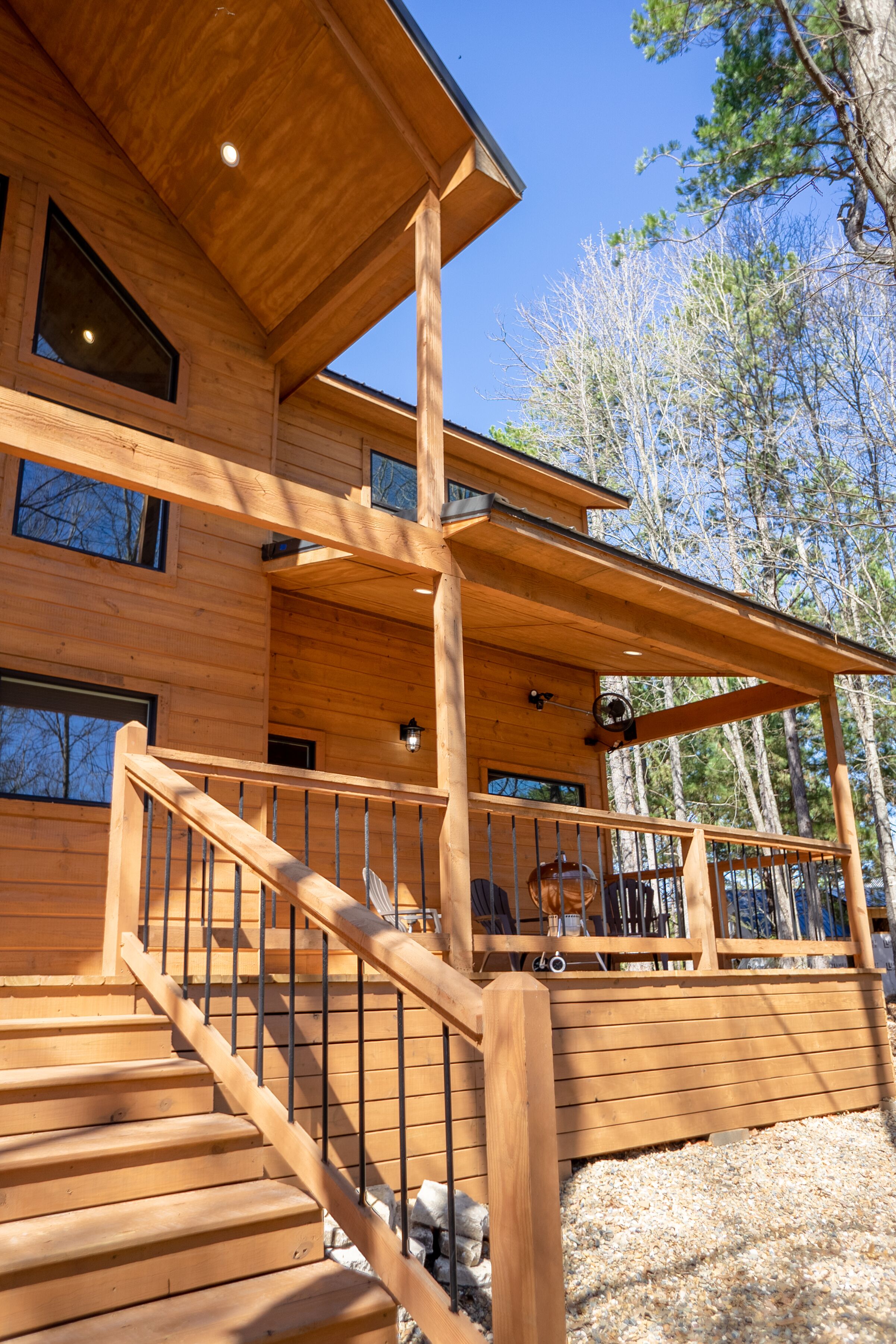 A wooden cabin with a covered deck and a staircase leading to the entrance.