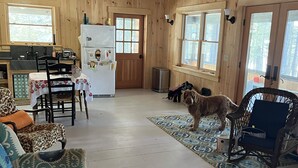 Ein gemütliches Blockhaus-Interieur mit Holzwänden, einem Essbereich, einer Küche und einem Wohnzimmer mit einem Hund.