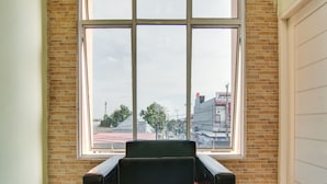 Een kamer met een groot raam, een zwarte stoel en een tafel.