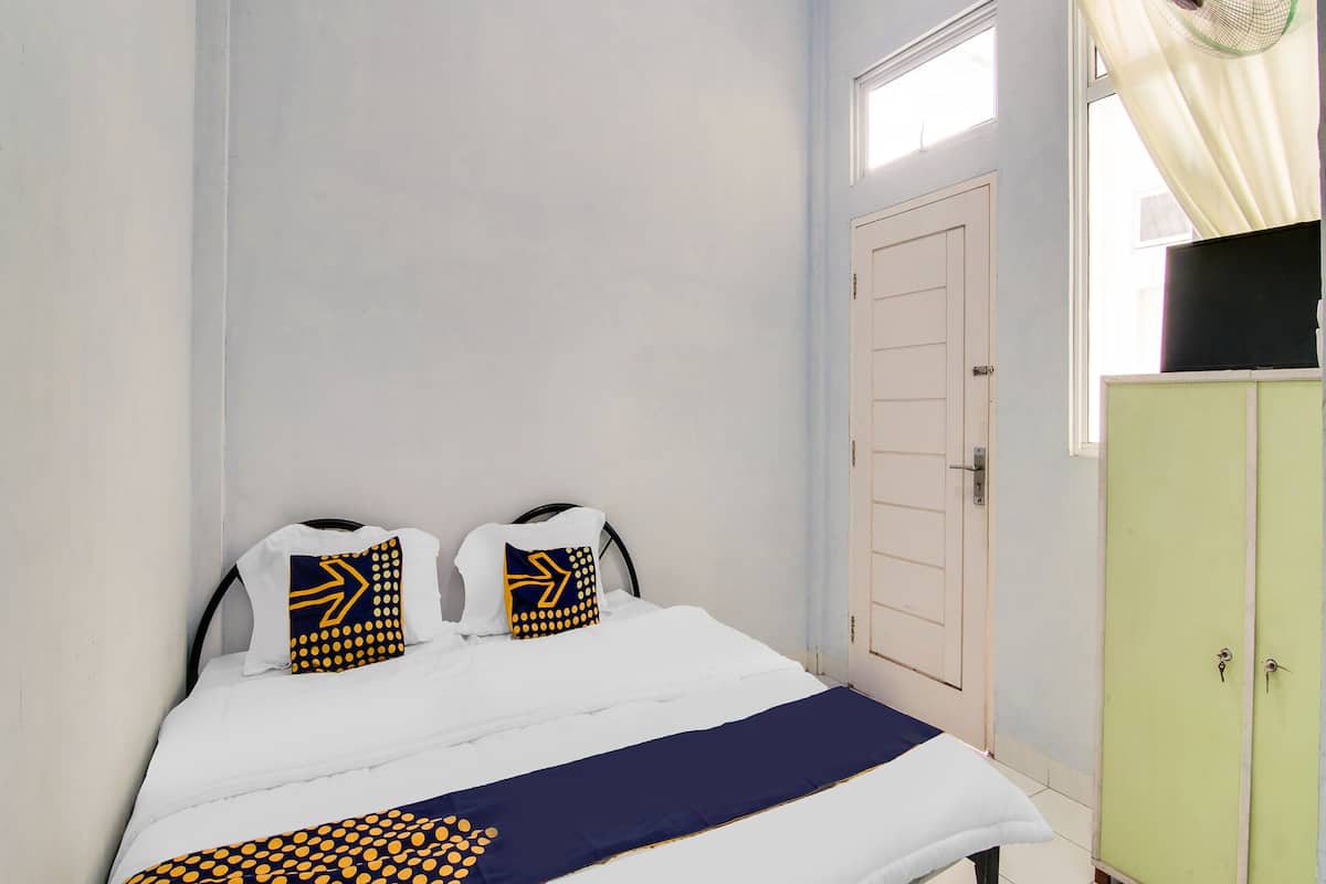 Ein Schlafzimmer mit einem Bett, zwei Kissen, einem Fenster, einer Tür und einem grünen Kleiderschrank.