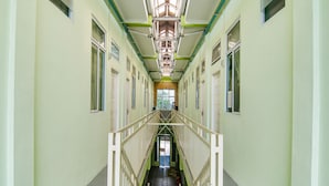 Een lange, smalle gang met aan weerszijden meerdere deuren, die leiden naar individuele kamers.