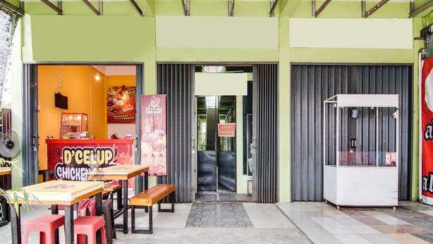 Een restaurant met een groen-wit kleurenschema, met een balie, zitgedeelte en een bedieningsluik.
