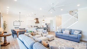 Ein geräumiges Wohnzimmer mit einem großen Sofa, einem blauen Couchen und einem Essbereich mit Tisch und Stühlen.