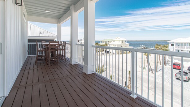 Eine überdachte Holzterrasse mit Blick auf Strand und Meer.