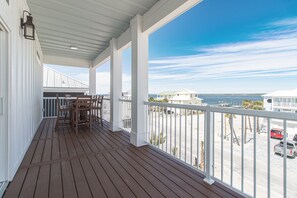 Una terraza cubierta de madera con vistas a la playa y al océano.