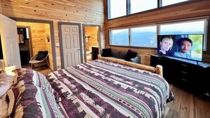 Een gezellige slaapkamer met een groot bed, een televisie en een raam met uitzicht op de omgeving.
