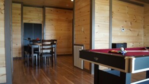 Een kamer met houten vloer, een pooltafel en een eethoek.
