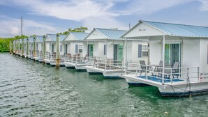A row of floating cottages with balconies and outdoor seating, docked along a waterway. - Treasure Harbor (Islamorada)