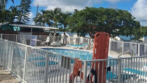 A pool area with a white fence, a lifebuoy, and palm trees in the background. - Treasure Harbor (Islamorada)