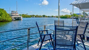 A boat with a covered deck, metal railings, and a table with chairs. - Treasure Harbor (Islamorada)