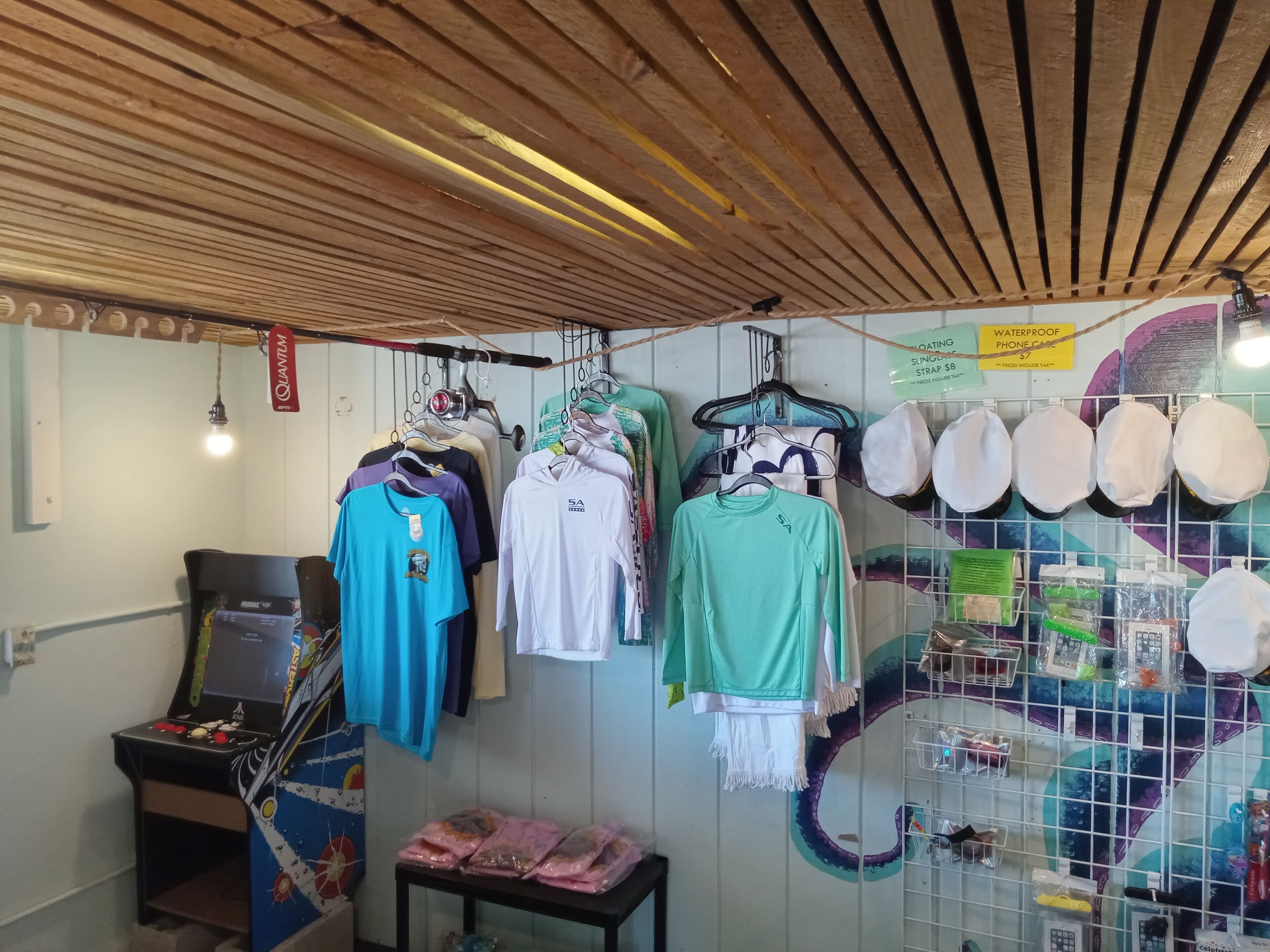 A retail space with clothing racks, a gaming machine, and various items on shelves.