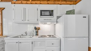 A kitchen with white cabinets, a microwave, a stove, and a refrigerator. - Treasure Harbor (Islamorada)