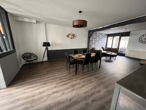 Un comedor moderno con una mesa y sillas de madera, una lámpara y un reloj de pared.