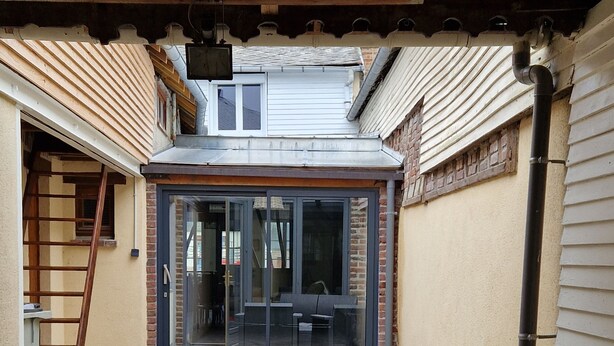 Un patio couvert avec une porte vitrée donnant sur un espace intérieur.