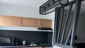 Une cuisine moderne avec des meubles en bois, un four encastré et un coin repas comprenant une table et des chaises en bois.