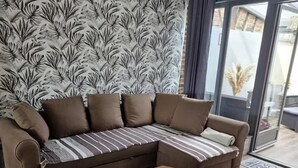 Un salon moderne avec un canapé d’angle, une table basse et un papier peint à motifs.