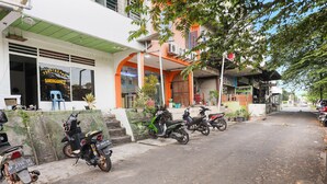 Une rue bordée de motos garées et un bâtiment sur lequel on peut lire l’inscription « PENGINAPIN SAWERIGADING ».