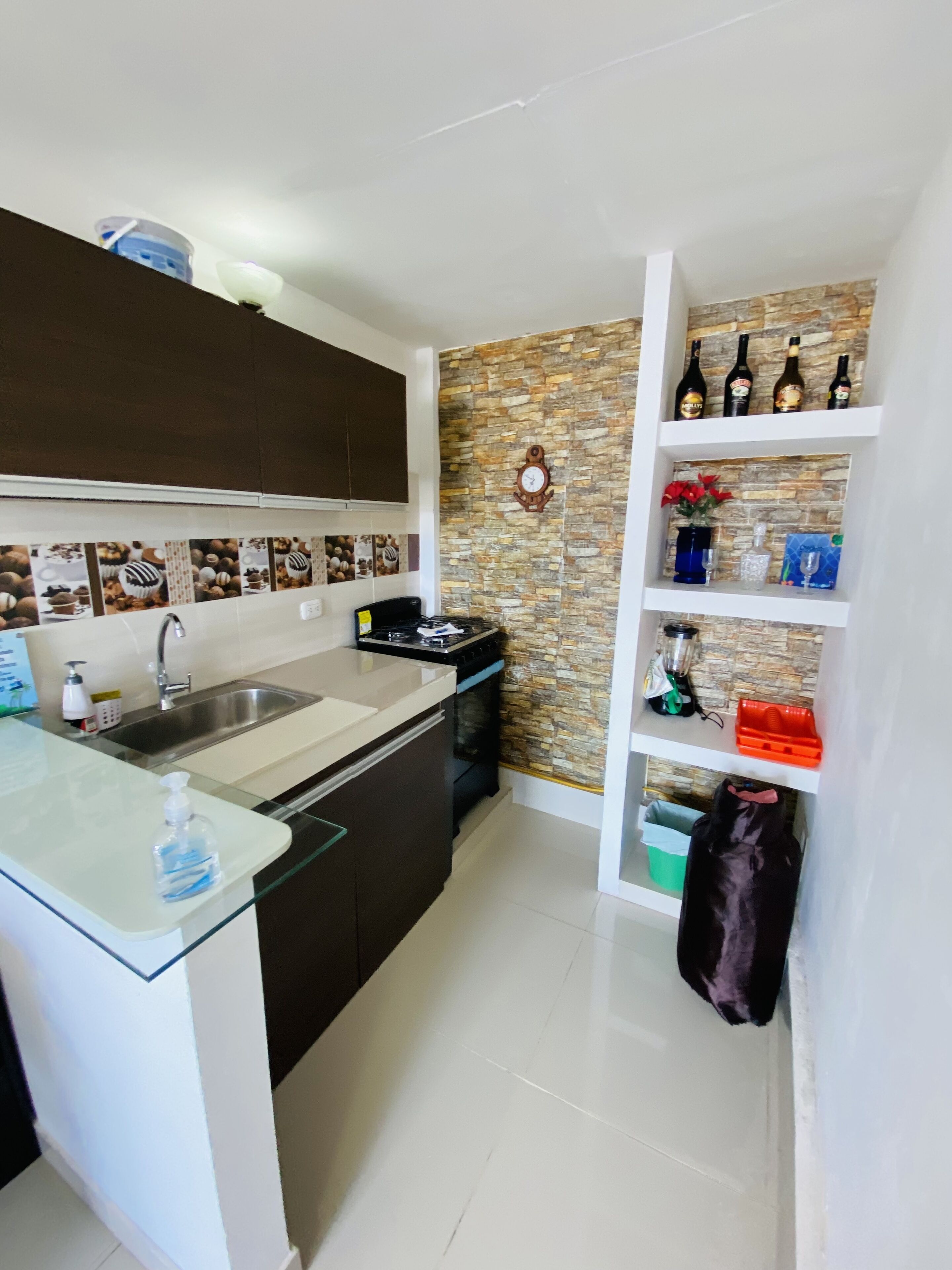 Cozinha moderna com ilha central, forno embutido e painel de parede de pedra.