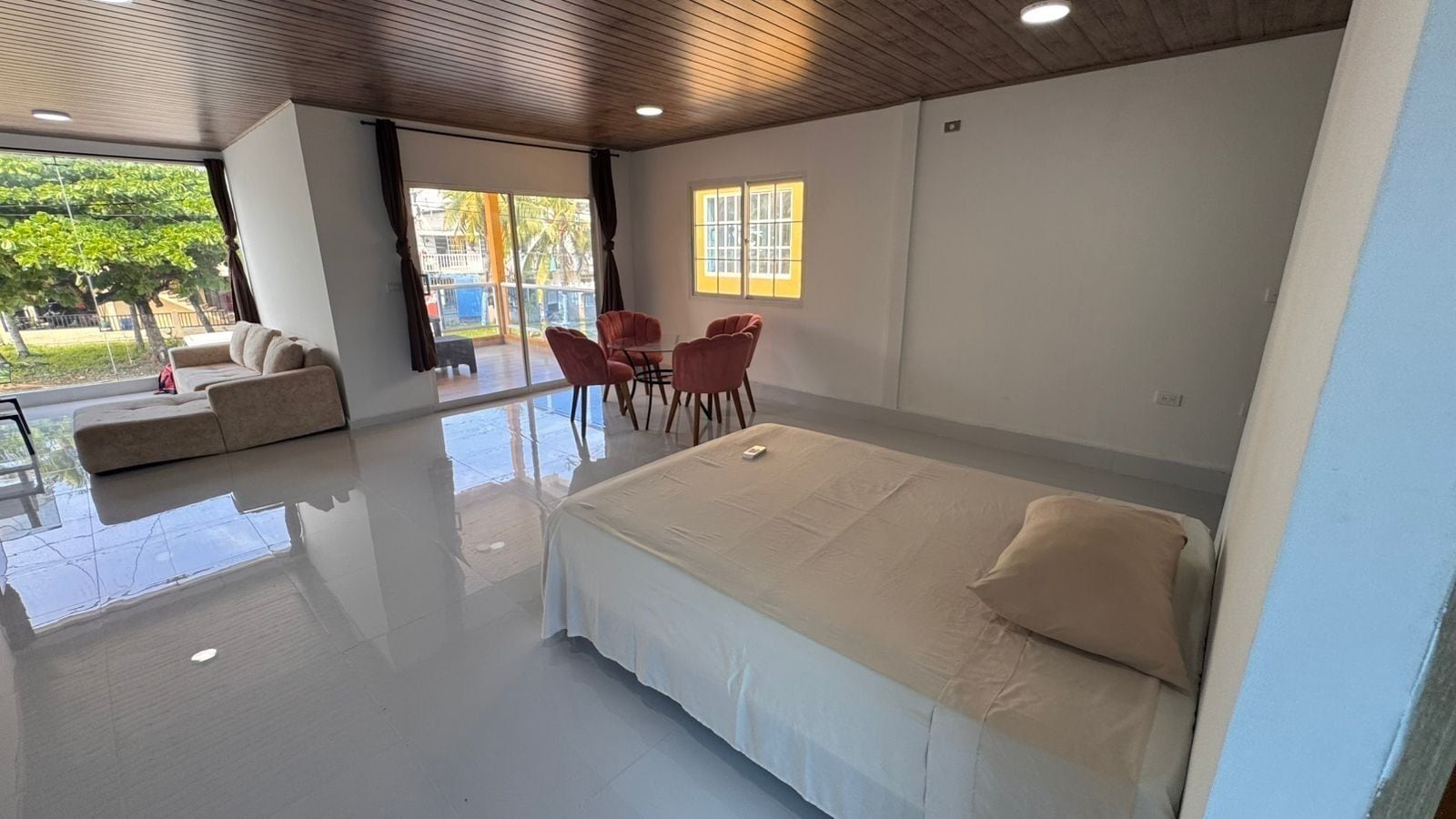 A modern bedroom with a large bed, a sofa, and a dining table with chairs.