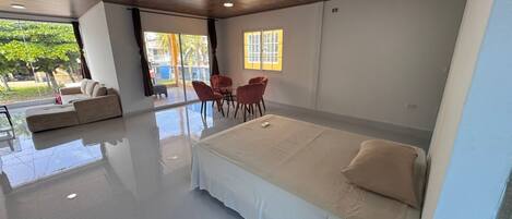 A modern bedroom with a large bed, a sofa, and a dining table with chairs.
