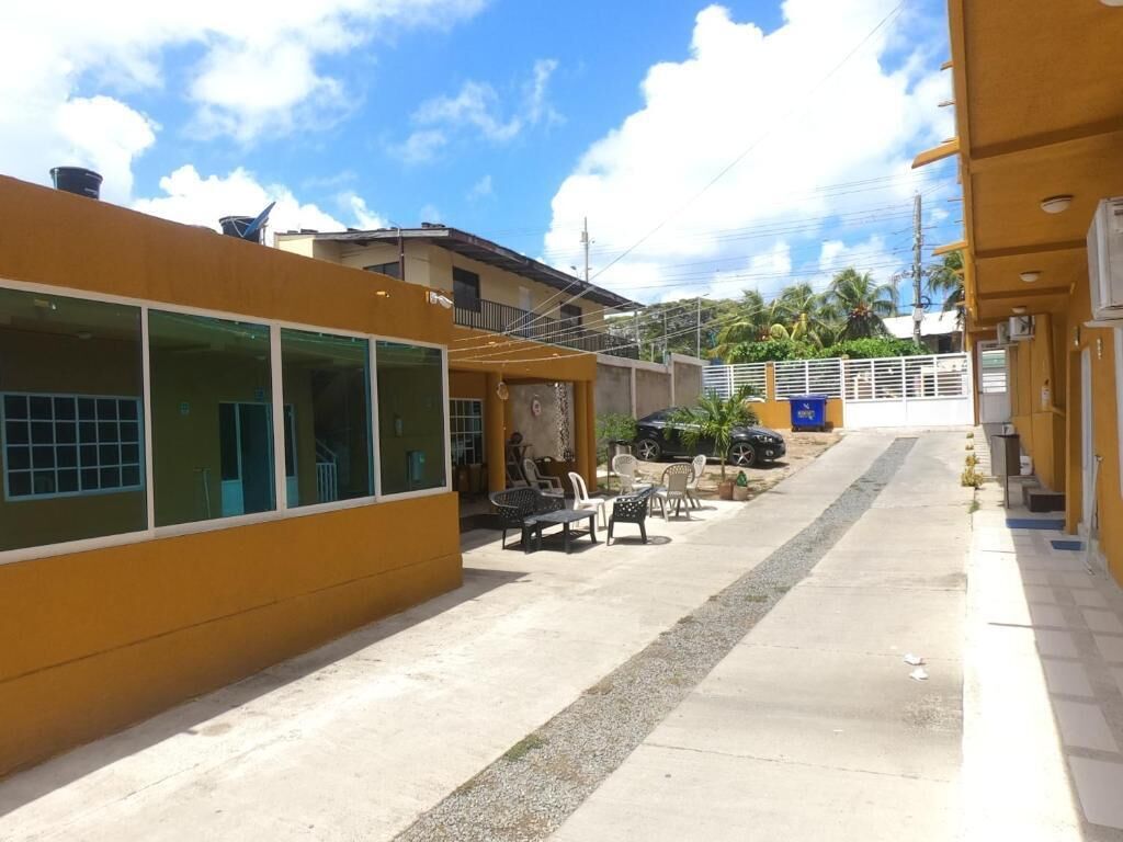 Um edifício com fachada amarela, grandes janelas e mesas ao ar livre.