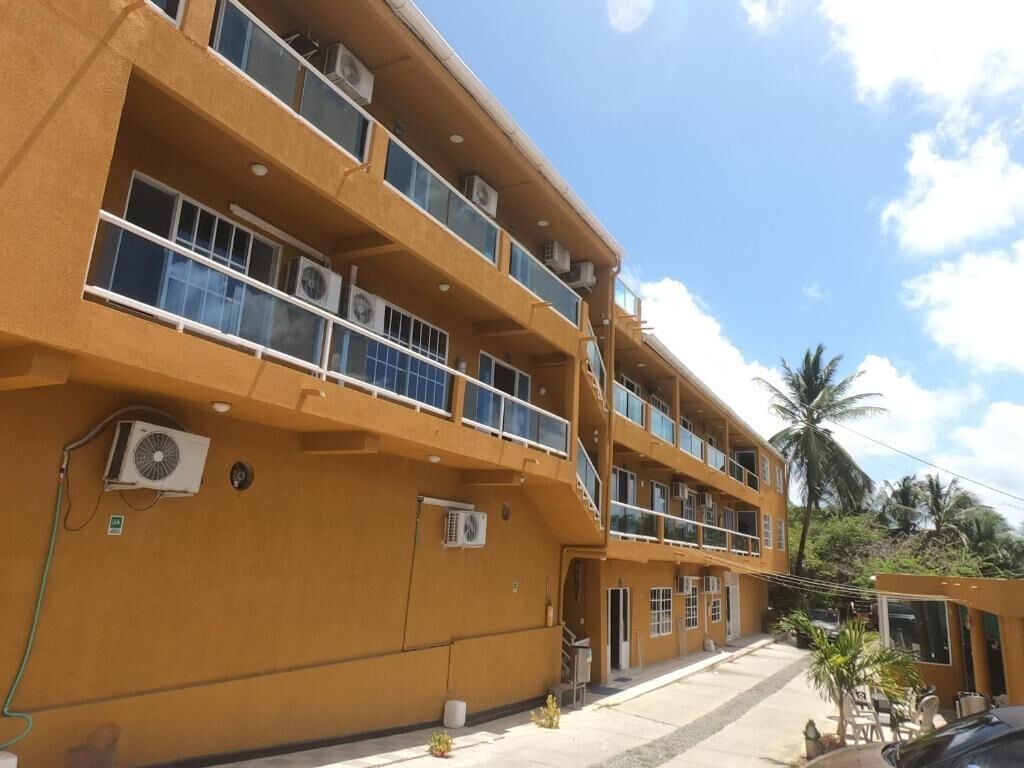 A multi-story building with balconies, air conditioning units, and a clear sky.