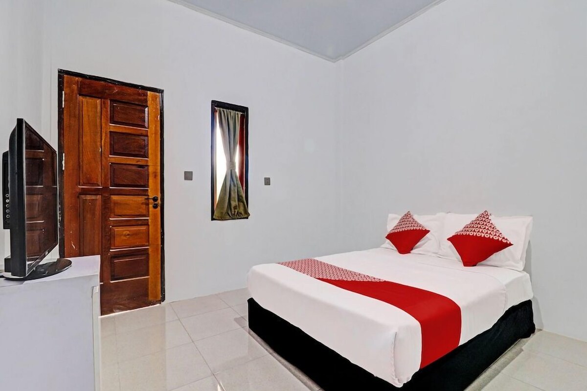 Une chambre d’hôtel avec un lit, une télévision, une porte en bois et un tableau au mur.