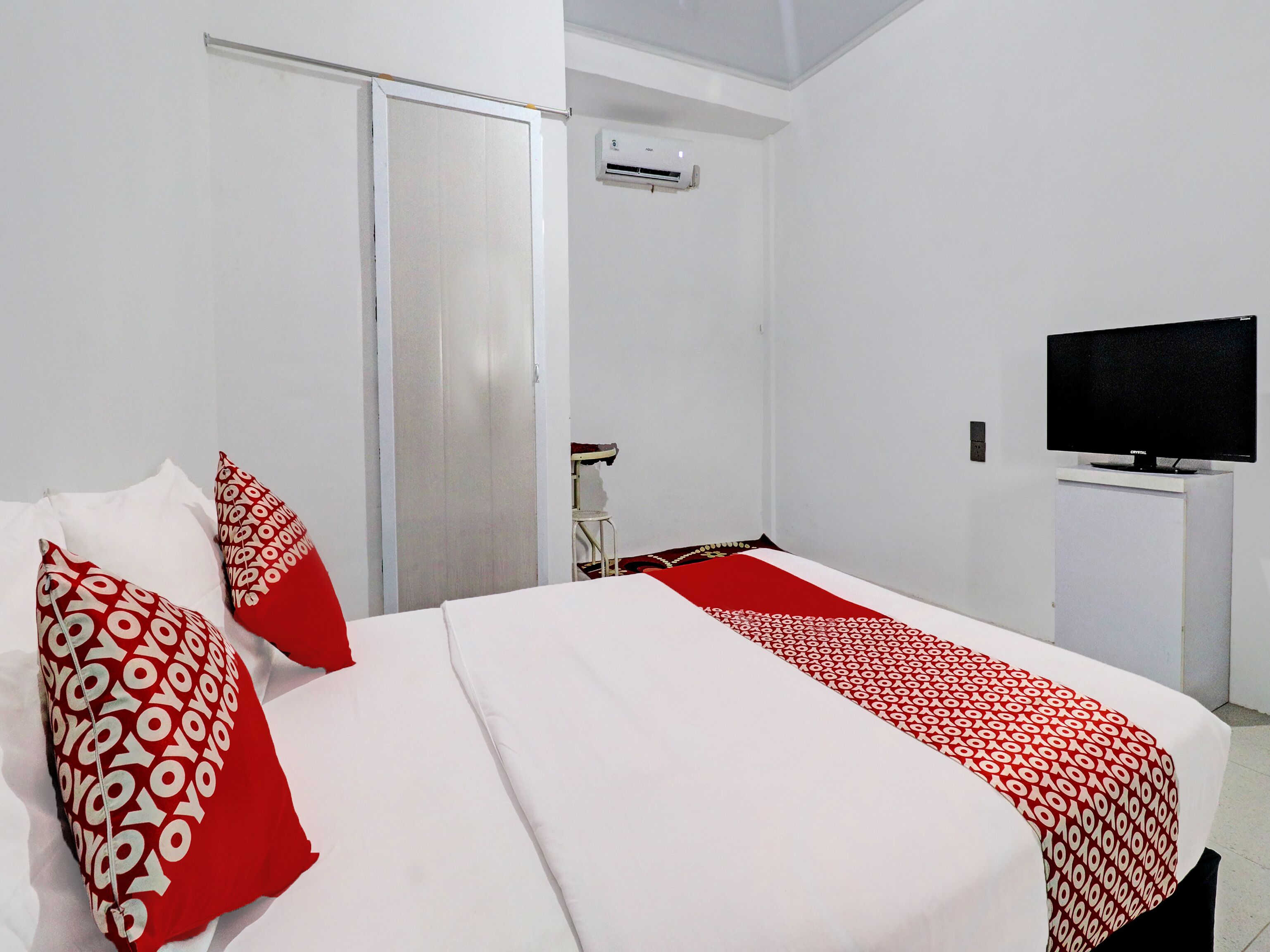 Ett hotellrum med en säng, en tv på ett stativ och en garderob.
