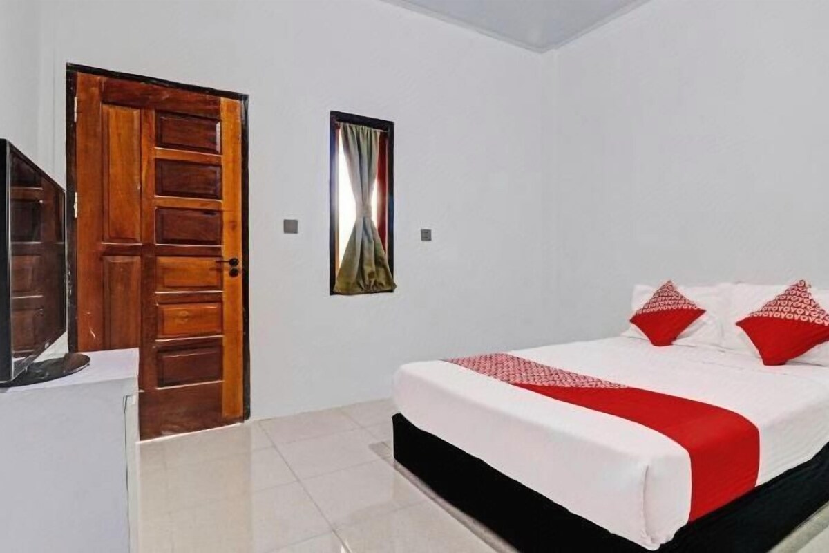 Une chambre d’hôtel avec un lit, une porte en bois, un téléviseur et un tableau au mur.