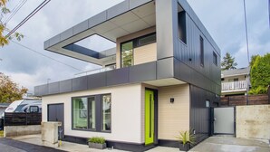 Een modern huis met twee verdiepingen, een plat dak, grote ramen en een groene deur.
