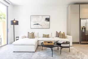 Ein modernes Wohnzimmer mit Ecksofa, Couchtisch, Stehlampe und Kühlschrank.