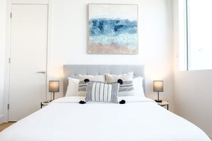 A hotel room with a large bed, two bedside lamps, a headboard, and a painting on the wall. - Modernista 2,  Townhome with Pool by Coconut Grove (Miami)