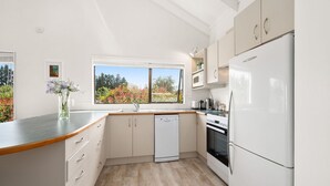 A modern kitchen with white cabinetry, a dishwasher, an oven, and a refrigerator. - Waitahanui Lake House - Lake Taupo Holiday Home (Waitahanui)