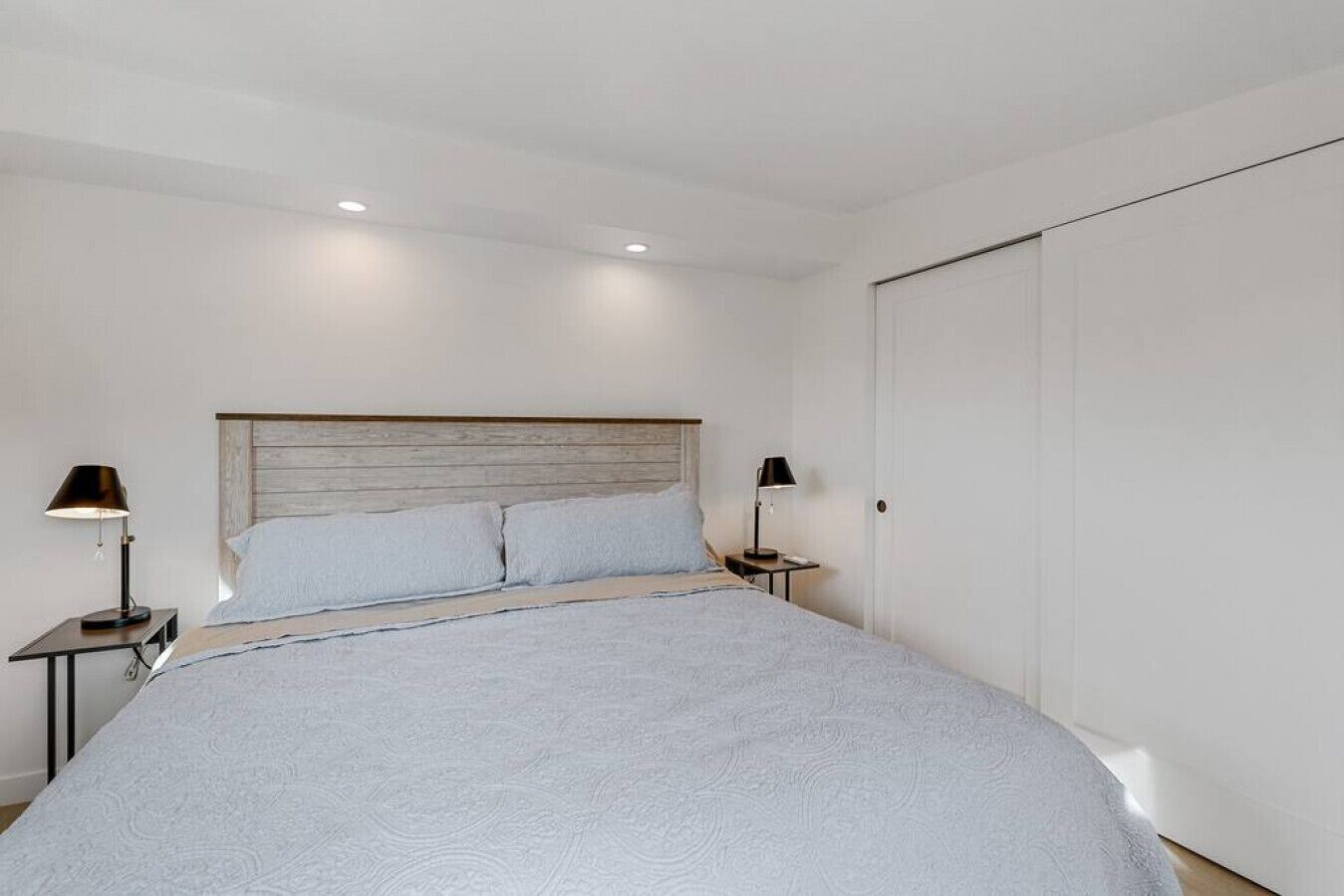 A bedroom with a large bed, two bedside tables, and a wardrobe.