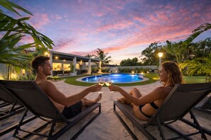 Two people reclining on lounge chairs facing a swimming pool, holding wine glasses. - Top Location • Near MIA & Dolphin Mall • Pool, BBQ (Miami)