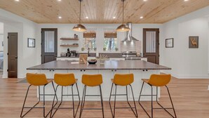 Una cocina amplia con una isla grande, techo de madera e iluminación colgante moderna.