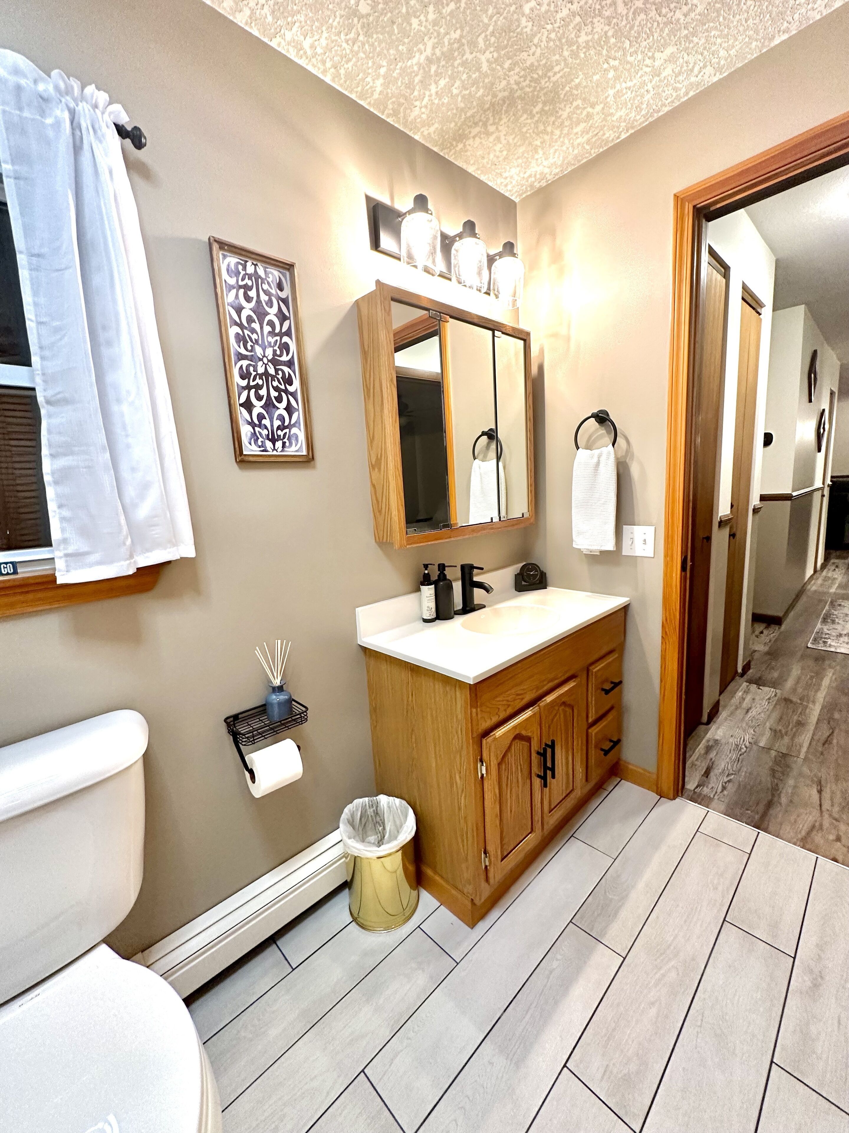 Une salle de bain avec un meuble-lavabo en bois, un miroir, des toilettes et un espace douche.