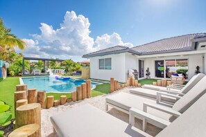 Una casa moderna con piscina, mobiliario exterior y césped bien cuidado.