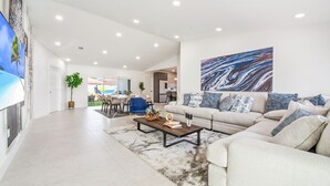 Un salon spacieux avec un grand canapé, une table basse et un tableau abstrait moderne accroché au mur.