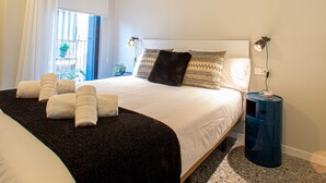 A bedroom with a bed, pillows, a nightstand, a lamp, and a window with curtains. - BARCELONA TOUCH APARTMENTS - ROSICH (L'Hospitalet de Llobregat)