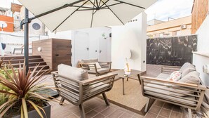 An outdoor patio area with two sofas, a table, and a large umbrella providing shade. - BARCELONA TOUCH APARTMENTS - ROSICH (L'Hospitalet de Llobregat)