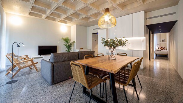A modern living room with a wooden dining table, grey sofa, and wicker chairs. - BARCELONA TOUCH APARTMENTS - ROSICH (L'Hospitalet de Llobregat)