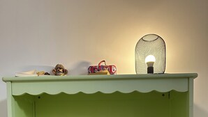 A green shelf unit with two white quilts, a small lamp, and various toys on top. - Spacious self-catering cottage near the beach for 16 people COTE DE GRANIT ROSE (Pleubian)