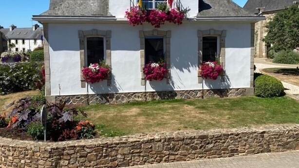 A white building with the sign "HOTEL DE VILLE" and French flags. It has flower boxes on the front and a stone wall in front. - Spacious self-catering cottage near the beach for 16 people COTE DE GRANIT ROSE (Pleubian)