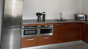 A kitchen with a stainless steel refrigerator, double ovens, wooden cabinets, a microwave, and a ceiling fan. - Spacious self-catering cottage near the beach for 16 people COTE DE GRANIT ROSE (Pleubian)