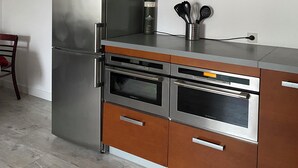 A modern kitchen with stainless steel appliances, wooden cabinets, and a built-in oven. - Spacious self-catering cottage near the beach for 16 people COTE DE GRANIT ROSE (Pleubian)