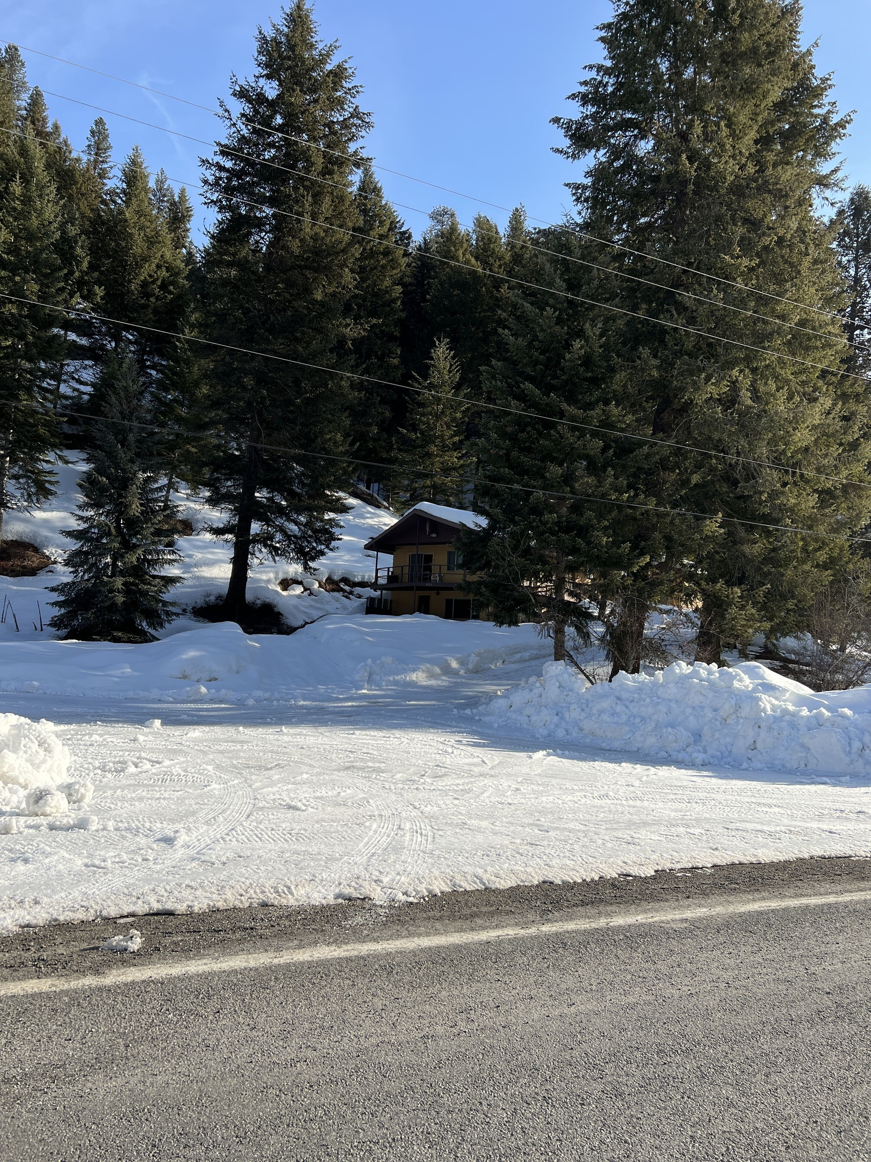 Una casa rodeada de árboles cubiertos de nieve y un cielo despejado.