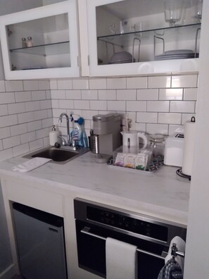 A compact kitchen with a built-in dishwasher, a coffee maker, and a kettle.