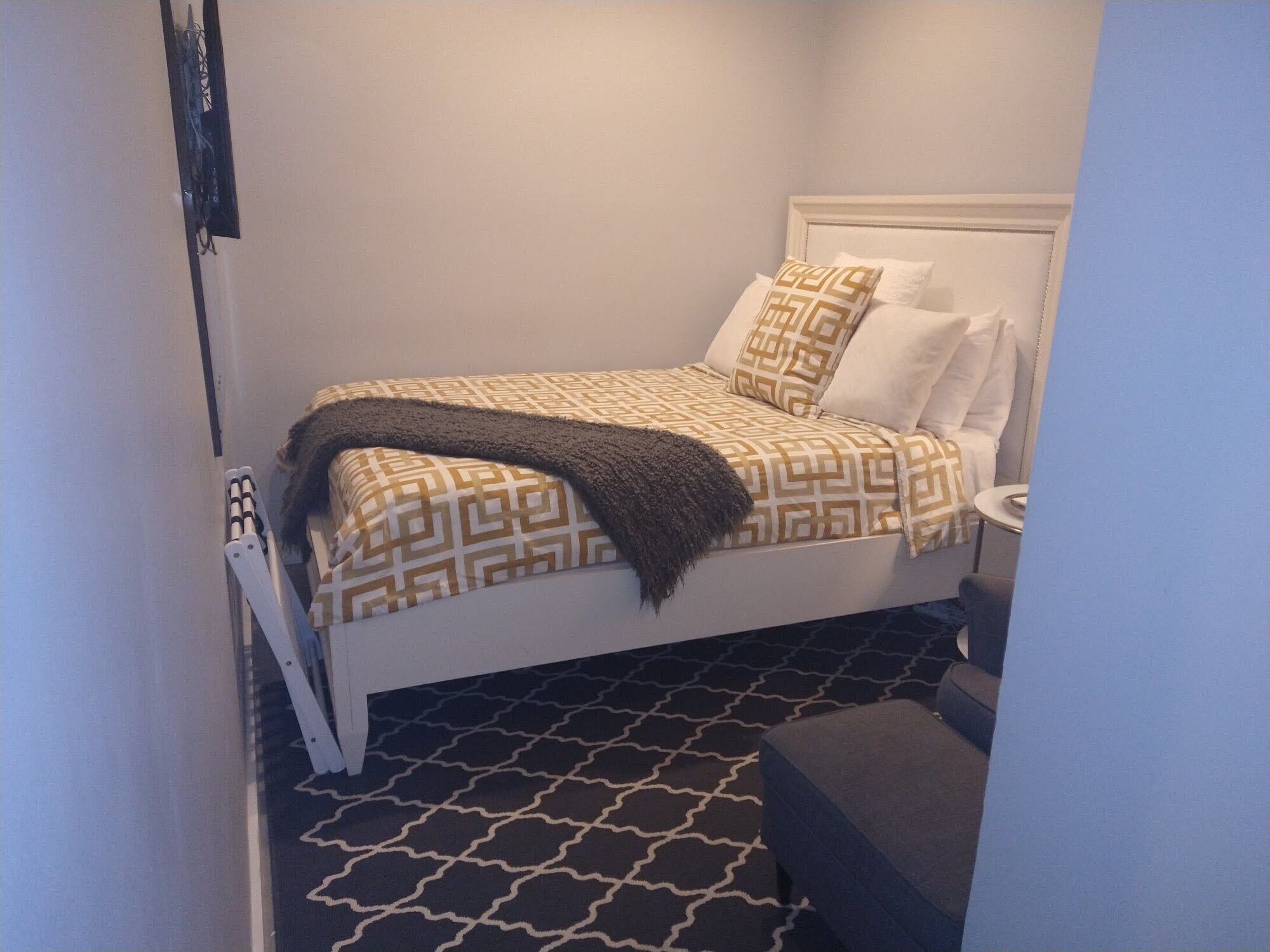 A neatly arranged bedroom with a bed, pillows, and a blanket.