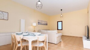 A modern living room with a dining area, a sofa, and a TV. - Home2Book Isla Lagoa, Private Pool (La Oliva)